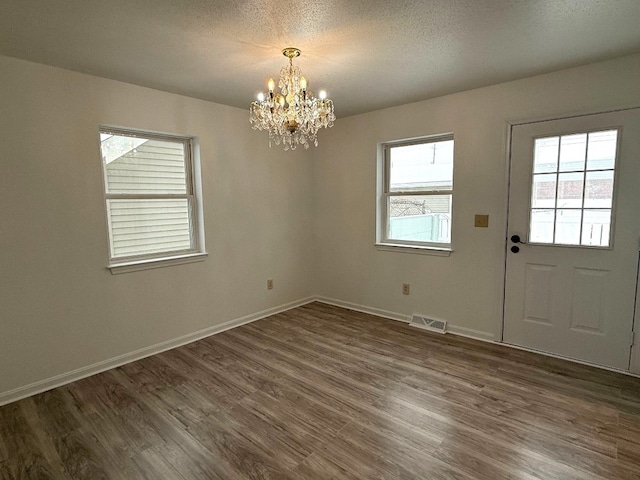 interior space featuring dark hardwood / wood-style floors, a textured ceiling, and a notable chandelier