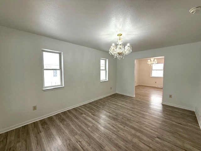 spare room featuring a healthy amount of sunlight, dark hardwood / wood-style floors, and a chandelier