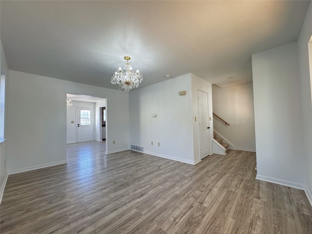 spare room featuring hardwood / wood-style flooring and a chandelier