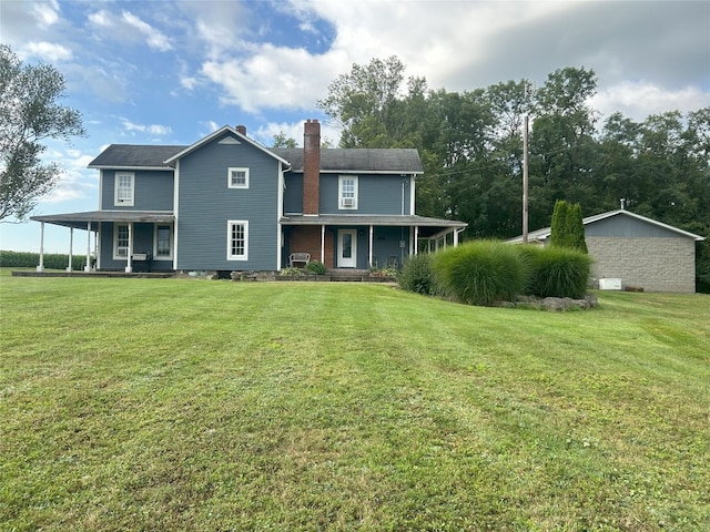 rear view of house featuring covered porch and a lawn