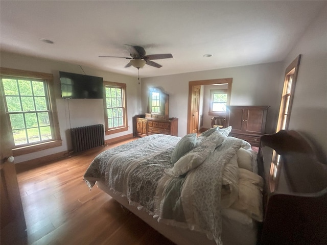 bedroom with radiator heating unit, light hardwood / wood-style floors, and ceiling fan