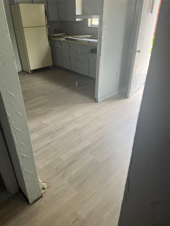 kitchen with gray cabinets, decorative backsplash, white refrigerator, and light hardwood / wood-style floors