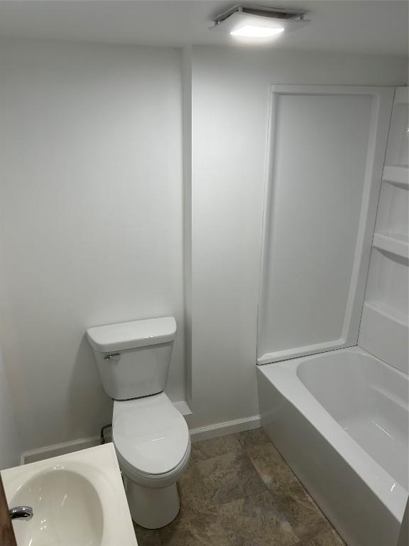 bathroom featuring a tub to relax in, toilet, and sink