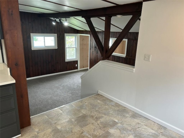 entrance foyer featuring lofted ceiling with beams, light colored carpet, and wooden walls