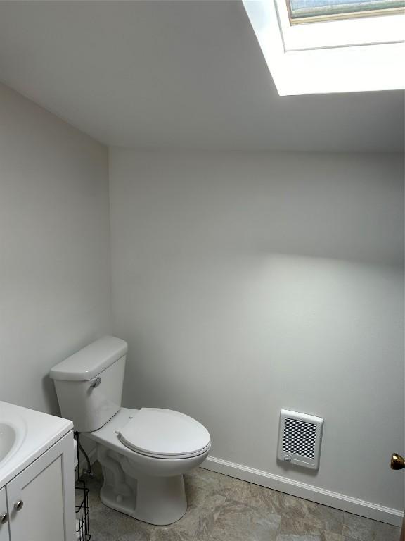 bathroom featuring vanity, a skylight, and toilet