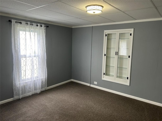 empty room with carpet flooring, a paneled ceiling, and crown molding