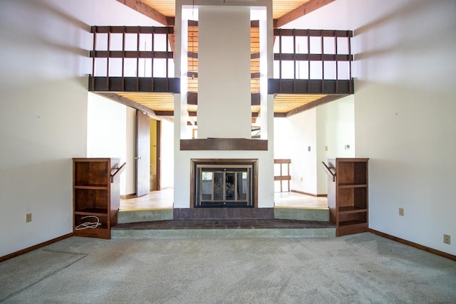 5130 W Stancliff Rd, Mckean, PA 16426 - unfurnished living room featuring a glass covered fireplace, carpet floors, a towering ceiling, and baseboards