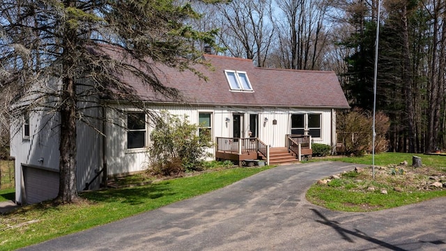 cape cod house with an attached garage, a shingled roof, and aphalt driveway