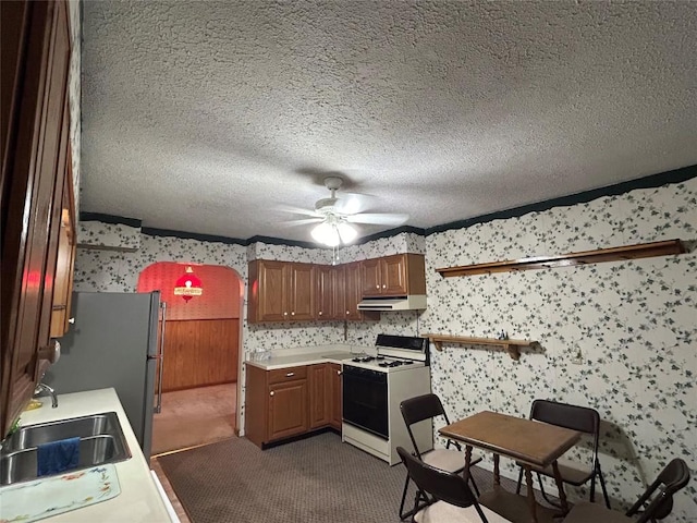 kitchen featuring carpet flooring, a textured ceiling, ceiling fan, sink, and white stove