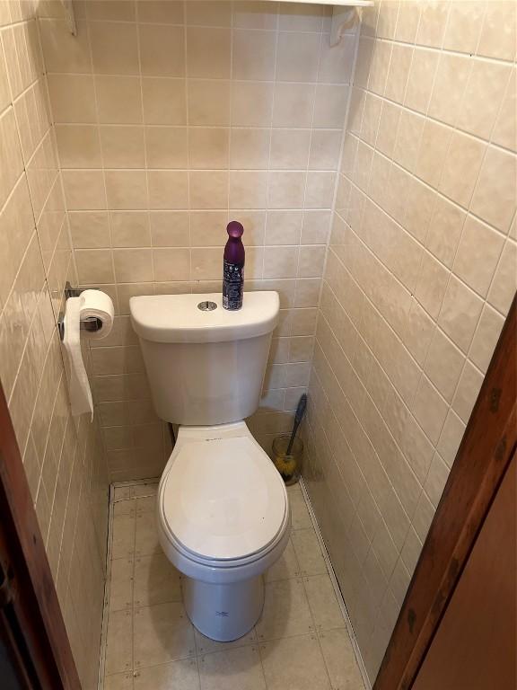 bathroom featuring toilet and tile walls