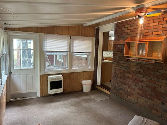 unfurnished living room with ceiling fan, lofted ceiling with beams, heating unit, wooden walls, and carpet