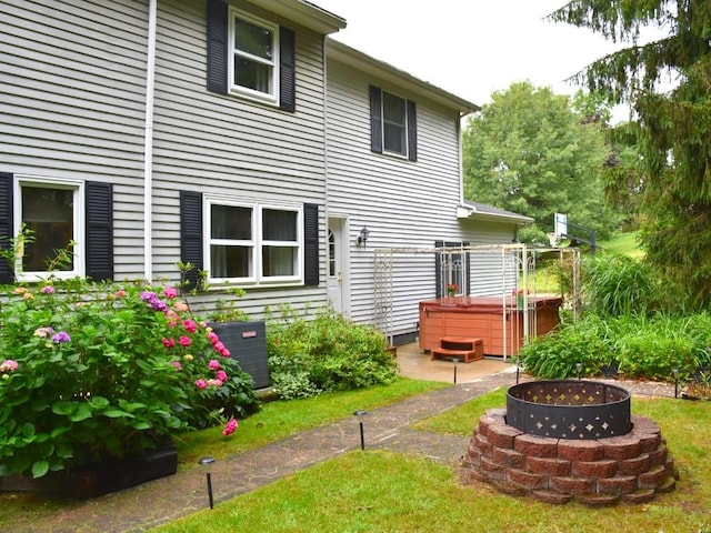 back of property featuring central air condition unit, a hot tub, and an outdoor fire pit