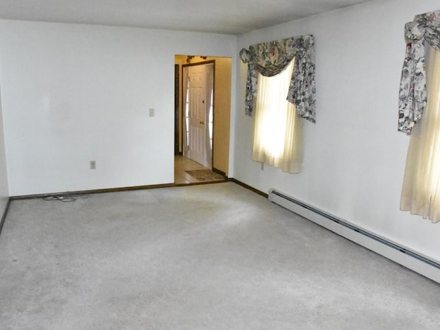 carpeted empty room with a baseboard heating unit and baseboards