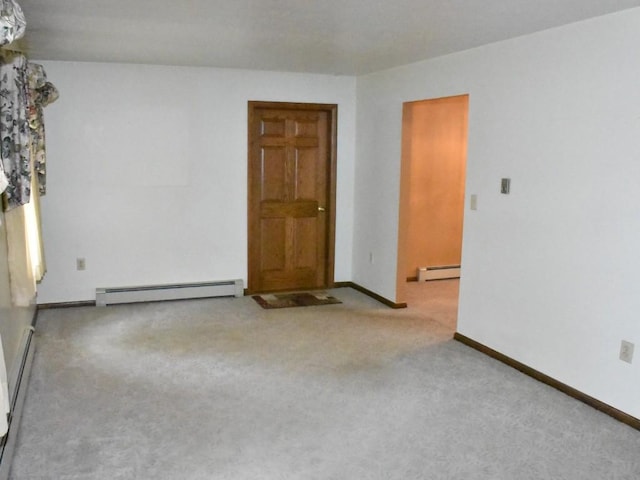 empty room featuring a baseboard heating unit, baseboards, and carpet flooring