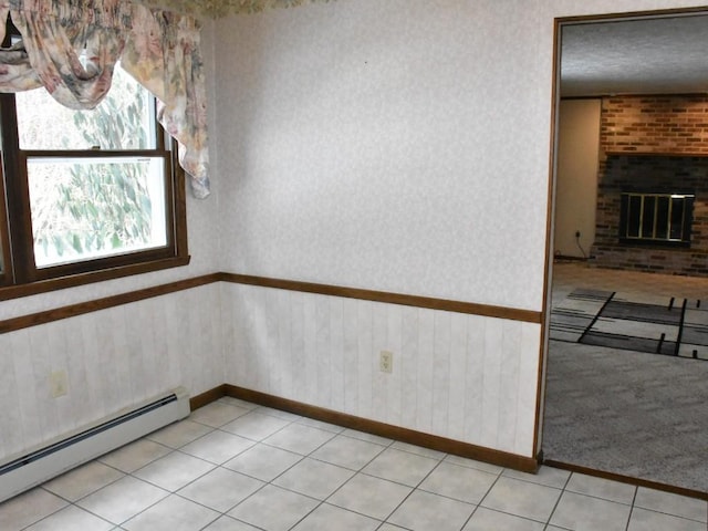 spare room featuring light tile patterned flooring, a brick fireplace, wallpapered walls, and a baseboard radiator