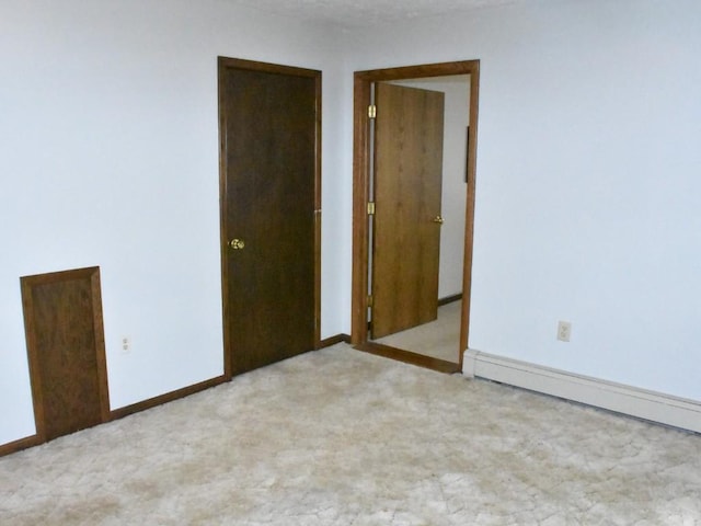 spare room with a baseboard heating unit, baseboards, and light carpet