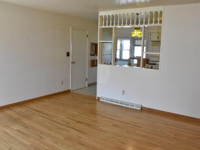 unfurnished room featuring baseboards, wood finished floors, and visible vents