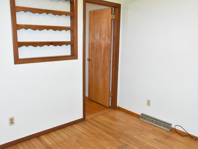 spare room featuring visible vents, light wood finished floors, and baseboards