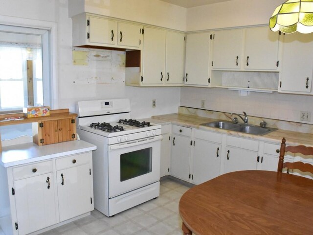 kitchen with tasteful backsplash, a sink, light floors, light countertops, and gas range gas stove