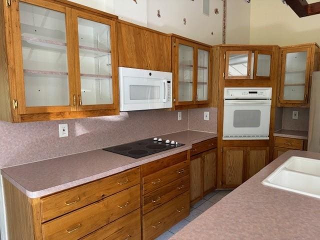 kitchen with sink, light tile patterned floors, white appliances, and backsplash