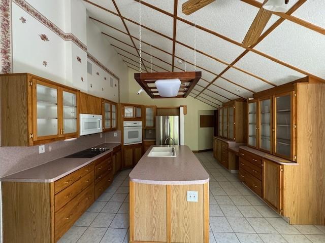 kitchen with a center island with sink, decorative backsplash, white appliances, and sink