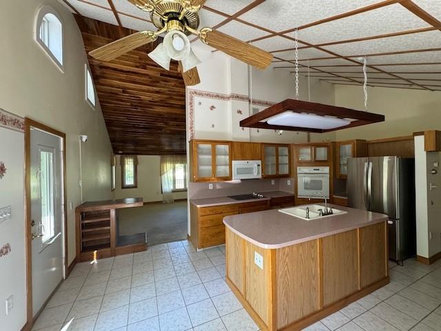 kitchen featuring ceiling fan, an island with sink, white appliances, and high vaulted ceiling