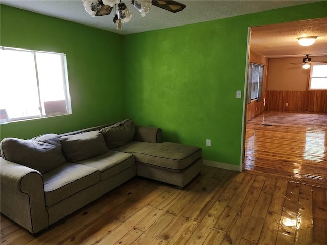 living room featuring wood walls, a textured ceiling, and light hardwood / wood-style flooring