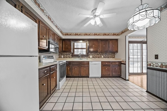 kitchen with sink, dark brown cabinets, white appliances, and pendant lighting