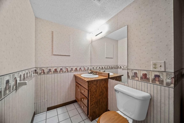 bathroom with vanity, toilet, a textured ceiling, and tile patterned flooring