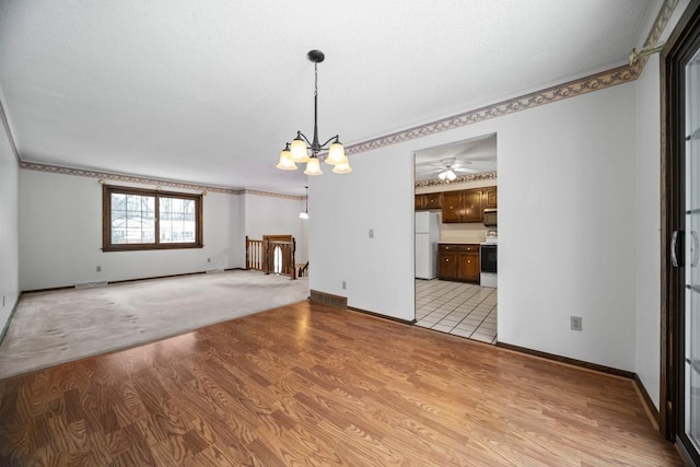 interior space featuring ceiling fan with notable chandelier and light hardwood / wood-style flooring