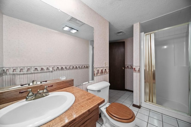 bathroom with a textured ceiling, tile patterned flooring, vanity, toilet, and walk in shower