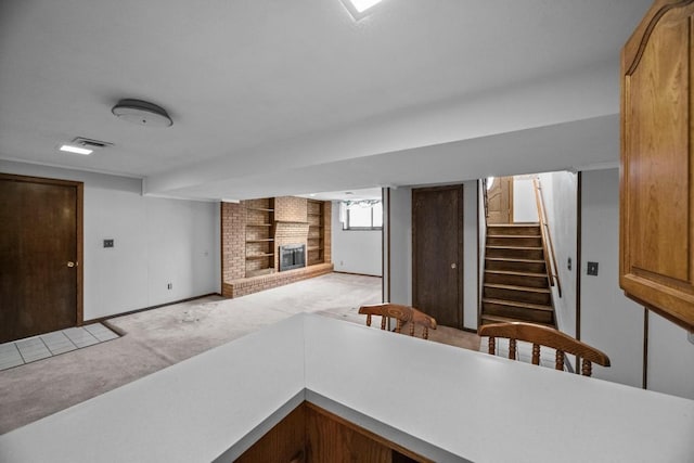 kitchen featuring a brick fireplace and light carpet