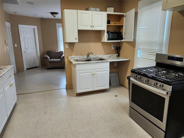 kitchen featuring white cabinetry, sink, radiator heating unit, and stainless steel gas range oven