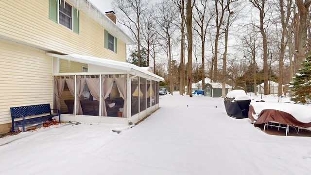 yard layered in snow featuring a sunroom