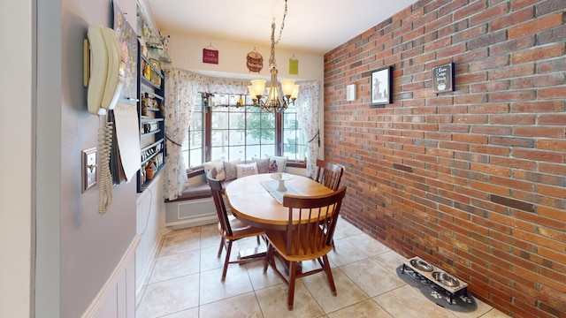 dining space featuring light tile patterned floors, brick wall, and a notable chandelier