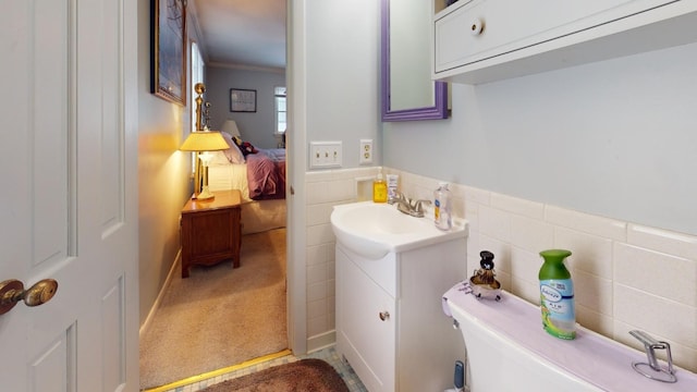 bathroom with crown molding, vanity, tile walls, and toilet