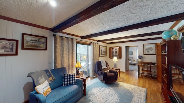 sitting room featuring beamed ceiling, wood-type flooring, and a textured ceiling