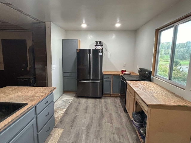 kitchen with stainless steel refrigerator, gray cabinets, wooden counters, and black / electric stove