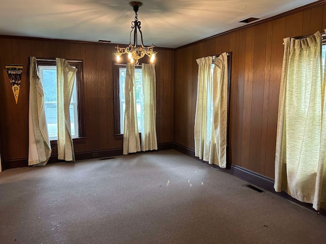 carpeted spare room with a notable chandelier