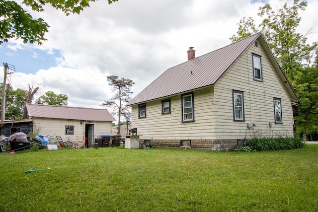 rear view of house featuring a lawn and an outdoor structure