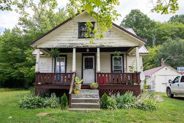 bungalow-style house with a porch, an outbuilding, and a front yard