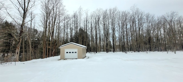 yard layered in snow with an outbuilding and a garage