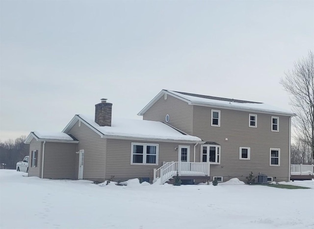 snow covered rear of property with central AC unit