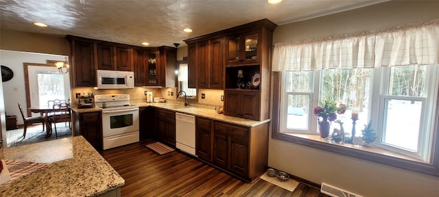 kitchen featuring light stone counters, sink, white appliances, and dark wood-type flooring