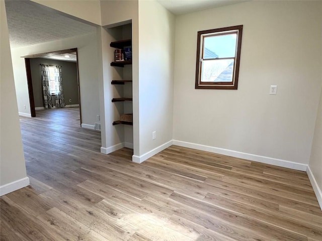 empty room featuring light wood-type flooring and baseboards