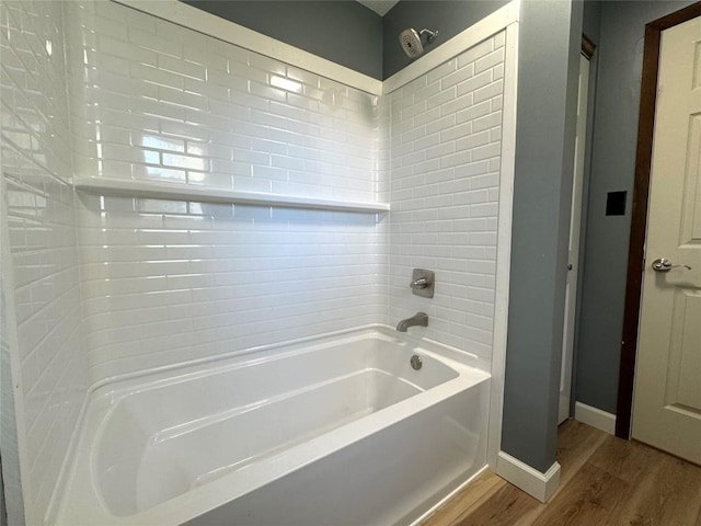 bathroom with shower / washtub combination, wood finished floors, and baseboards