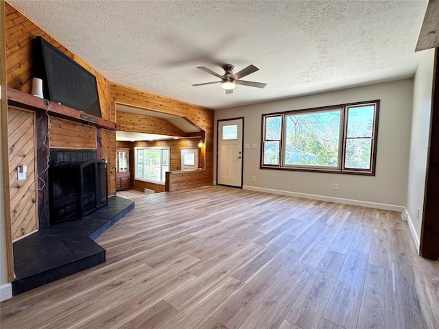 unfurnished living room featuring a textured ceiling, a healthy amount of sunlight, light wood finished floors, and baseboards