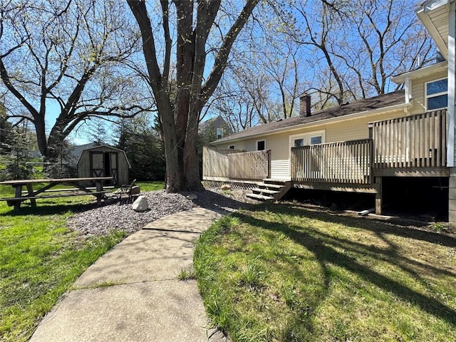 exterior space featuring a lawn, a shed, a wooden deck, and an outbuilding