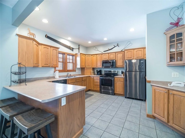 kitchen featuring stainless steel appliances, a sink, a peninsula, a kitchen bar, and glass insert cabinets