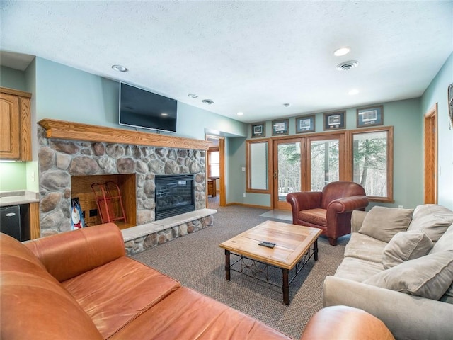 living area featuring a textured ceiling, visible vents, recessed lighting, carpet, and a fireplace